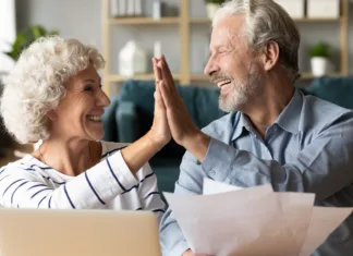 Upokojence čaka v juniju dodatno nakazilo Excited older couple giving high five, mature family celebrating success, checking or paying domestic bills, planning budget, smiling mature man holding financial documents, reading good news