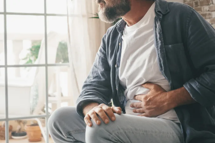 man-suffering-with-severe-stomach-pain-sitting-at-home-hand-of-mature-guy-holding-abdomen-suffering-from-ache-diarrhea-or-indigestive-problem-caucasian-guy-pressing-on-belly-on-painful-sensation-stockpack-istock Man suffering with severe stomach pain sitting at home. Hand of mature guy holding abdomen suffering from ache, diarrhea or indigestive problem. Caucasian guy pressing on belly on painful sensation