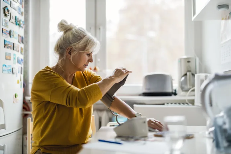 Senior woman measuring blood pressure at home