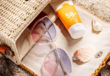 Večina dela to napako: številka na sončni kremi ne pomeni tega, kar mislite Sunscreen and glasses in a wicker straw bag on a sandy beach