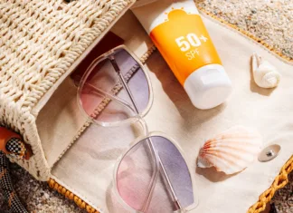 Večina dela to napako: številka na sončni kremi ne pomeni tega, kar mislite Sunscreen and glasses in a wicker straw bag on a sandy beach