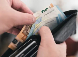 Na račune prihaja vračilo dohodnine: preverite, na kateri bančni račun bo FURS nakazal denar close-up view of hands taking money out of a wallet, spending cash concept