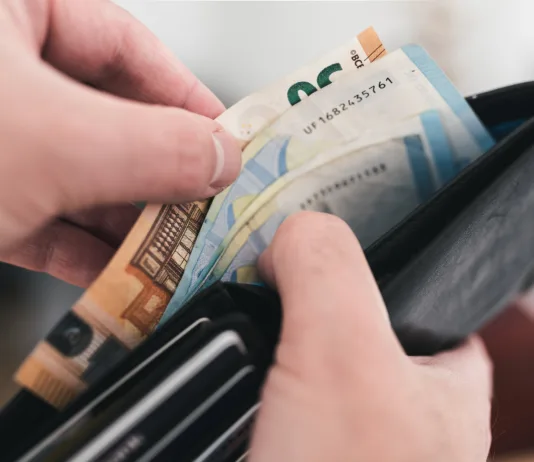 Na račune prihaja vračilo dohodnine: preverite, na kateri bančni račun bo FURS nakazal denar close-up view of hands taking money out of a wallet, spending cash concept