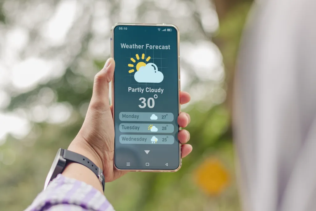 A young Muslim woman checking the weather forecast using an app on her smartphone outdoors