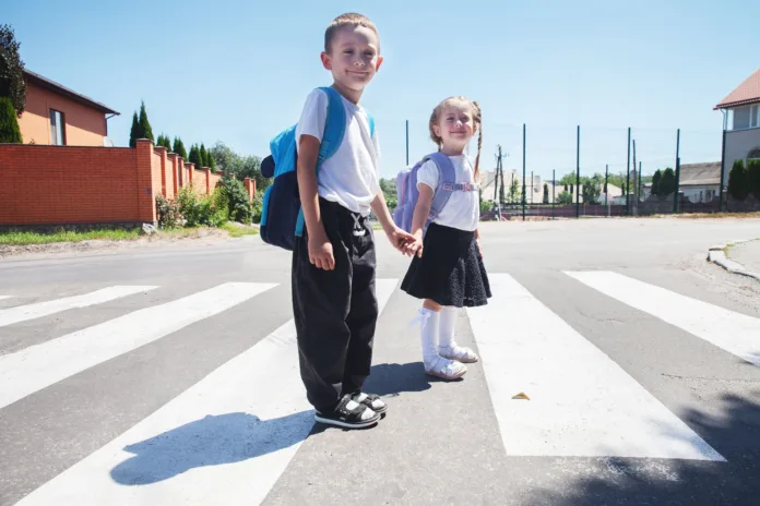 brother-and-sister-holding-hands-safely-cross-a-pedestrian-crossing-with-backpacks-on-their-way-to-school-on-a-sunny-morning-stockpack-istock Brother and sister holding hands safely cross a pedestrian crossing with backpacks on their way to school on a sunny morning