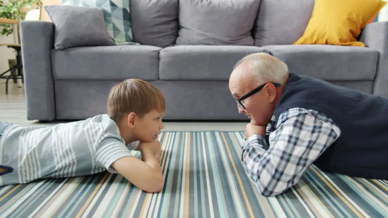 Grandfather and grandson lying on living room floor