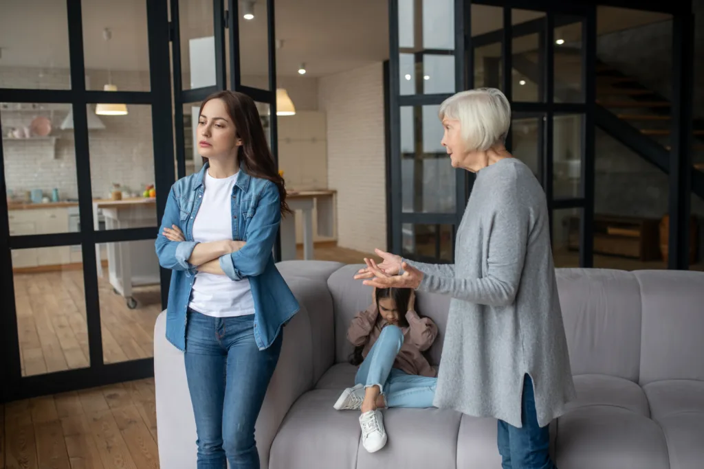 Argument is in dispute. Caring and smart grandmother speaking arguments to her adult daughter, granddaughter covering her ears sitting on the couch.