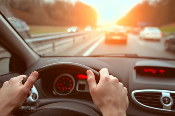 driving-on-highway-road-closeup-hands-of-car-driver-on-steering-wheel-road-trip-at-sunset-stockpack-istock driving on highway road, closeup hands of car driver on steering wheel, road trip at sunset