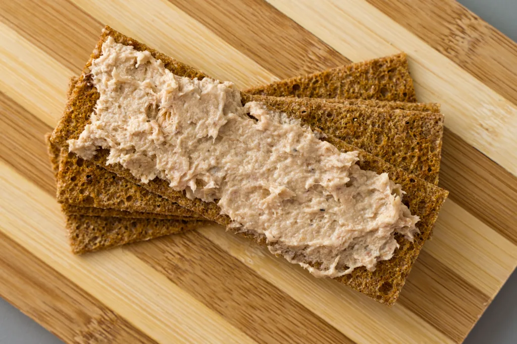 Fish rillette on crispy bread lies on a wooden board