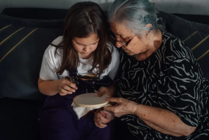 grandmother-teaching-her-granddaughter-the-art-of-cross-stitch-embroidery-sharing-a-moment-of-connection-and-creativity-stockpack-istock Grandmother teaching her granddaughter the art of cross-stitch embroidery, sharing a moment of connection and creativity