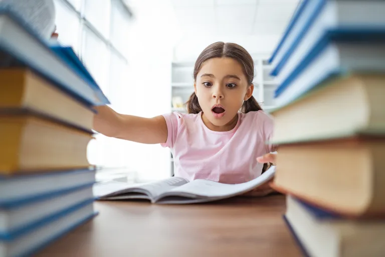 The surprised schoolgirl sitting on the desk with books