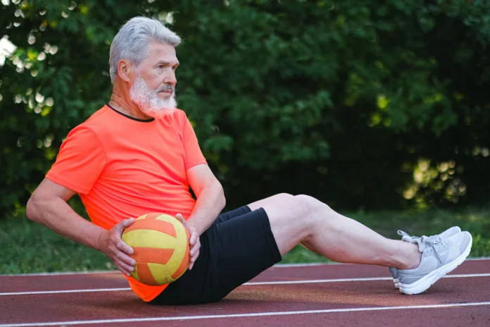 Aged man doing sport exercise with ball