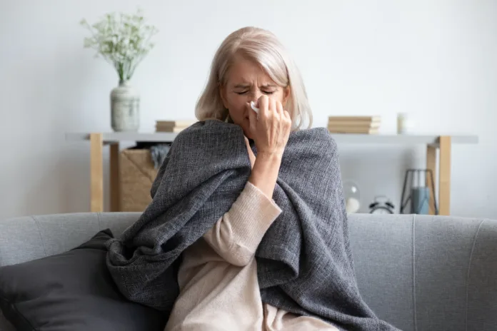 middle-aged-50s-sick-frozen-woman-seated-on-sofa-in-living-room-covered-with-warm-plaid-sneezing-holding-paper-napkin-blow-out-runny-nose-feels-unhealthy-seasonal-cold-weakened-immune-system-concept-stockpack-istock Middle-aged 50s sick frozen woman seated on sofa in living room covered with warm plaid sneezing holding paper napkin blow out runny nose feels unhealthy, seasonal cold, weakened immune system concept