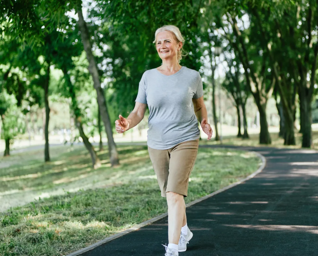 Smiling active senior woman jogging running and walking doing fitness in the park